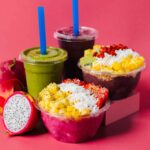 Palm Berries' açaí bowls and smoothies with ingredients with pink background.