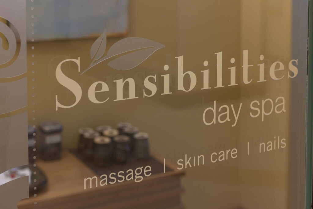 Glass door with words "Sensibilities Day Spa, massage, skin care, nails."